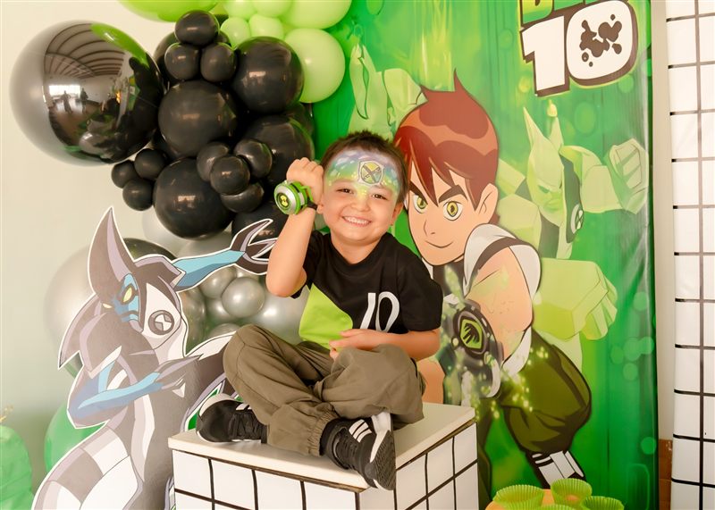 Niño de cinco años con la cara pintada mostrando su reloj en su fiesta de Ben 10