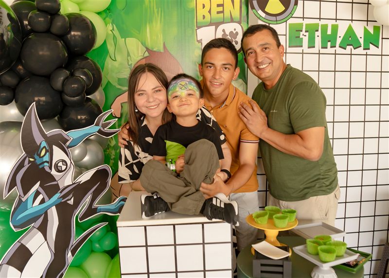 Niño cumpleañero con la cara pintada abrazado por su familia en su fiesta de Ben 10