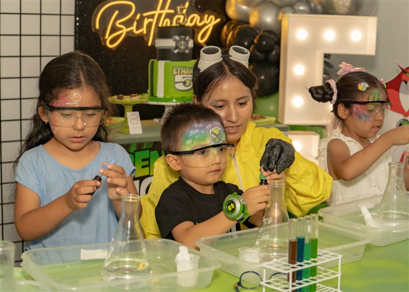 Niños con gafas de laboratorio y la cara pintada en un taller de ciencia en una fiesta de Ben 10