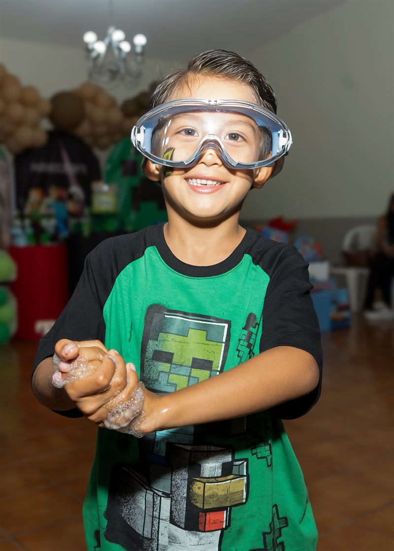 Niño con gafas protectoras y las manos con espuma en una fiesta de Minecraft