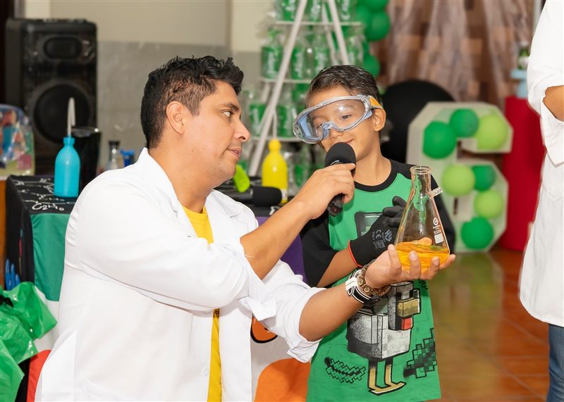 Niño con gafas protectoras en un experimento con un científico animador