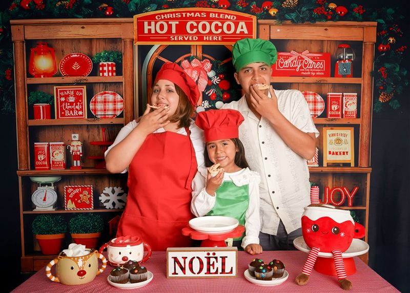 Tres hermanos con gorros de cocinero comiendo galletas en un set navideño de chocolate caliente