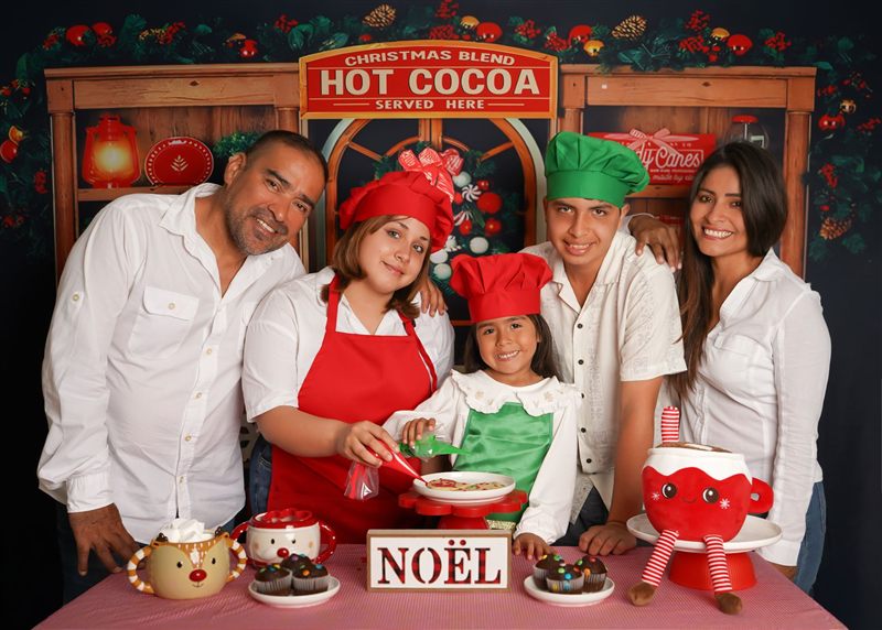 Familia de cinco con gorros de cocinero decorando galletas en el set navideño Hot Cocoa