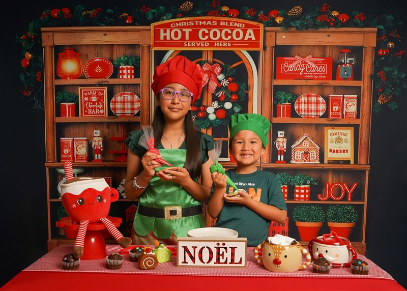 Hermanos con gorros de cocinero sosteniendo mangas pasteleras en el set navideño