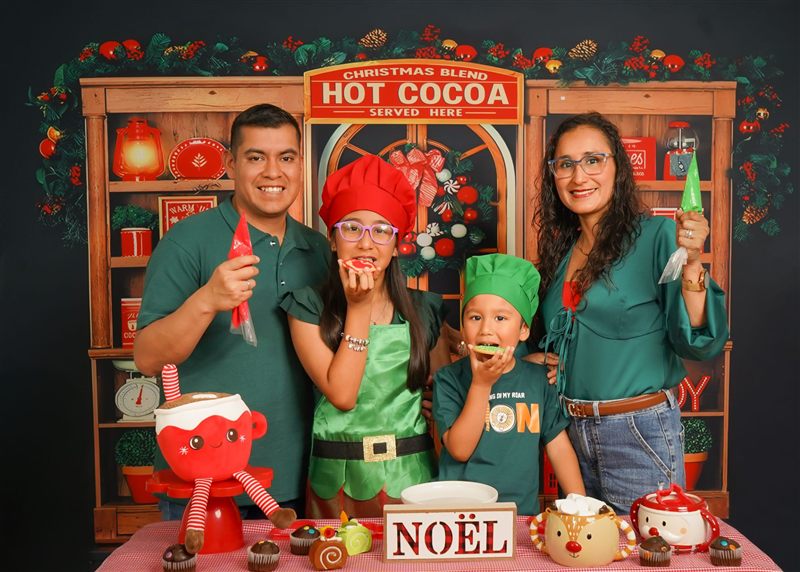 Familia con ropa verde y gorros de cocinero comiendo galletas navideñas