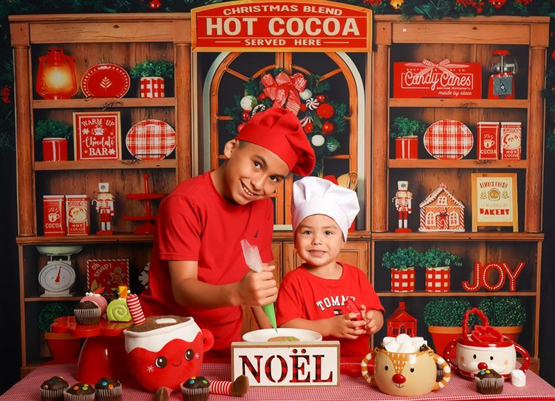 Dos hermanos con camisetas rojas decorando una galleta en el set navideño