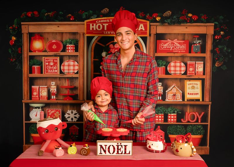 Joven y su hermano pequeño con pijamas navideñas decorando galletas